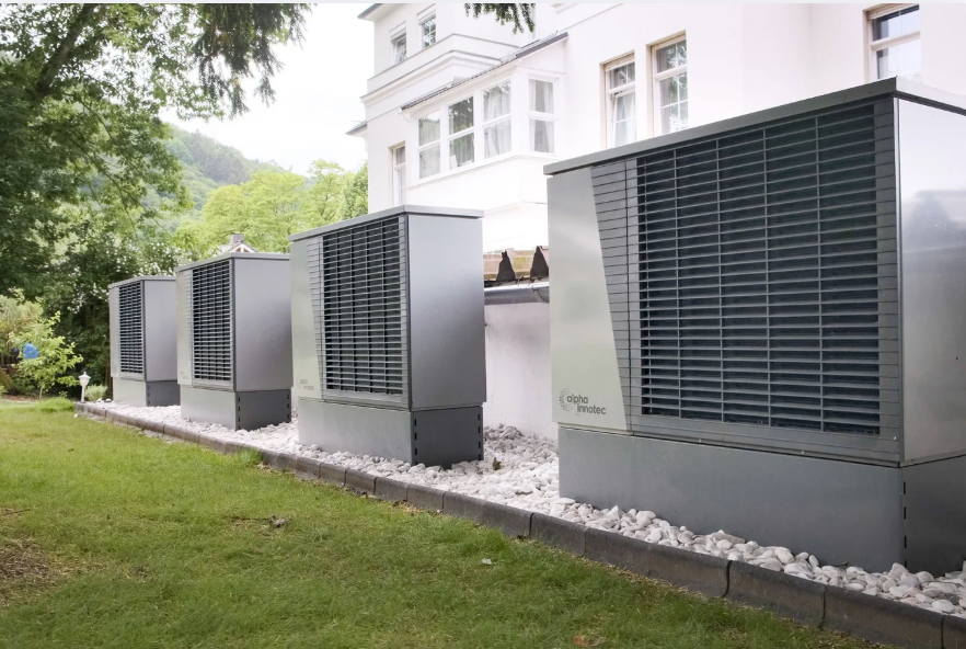 Outdoor heat pumps in front of a large white house